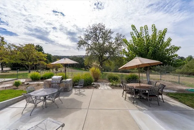 a view of a patio with chairs and tables under an umbrella