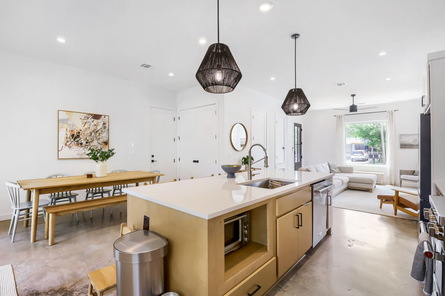 4804 Ribbecke Avenue, Unit A Austin, TX 78721 - Photo 11 of 32 This bright and spacious open-concept living area features a modern kitchen island with a sink and pendant lighting, polished concrete flooring, and a large window providing ample natural light