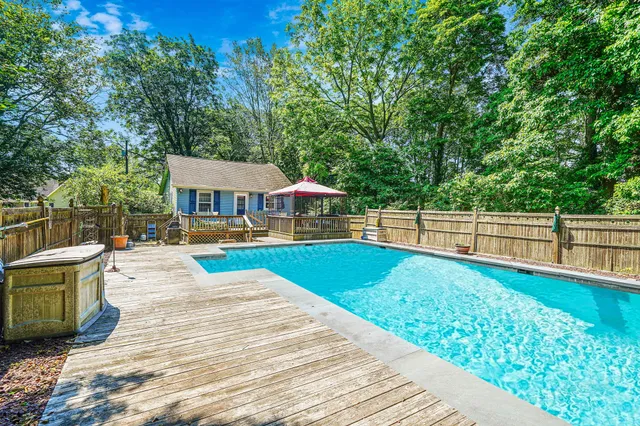 a view of house with swimming pool outdoor seating and trees in the background
