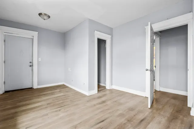 a view of an empty room with wooden floor and closet