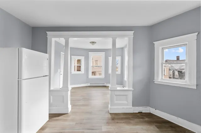a view of an empty room with wooden floor and a window
