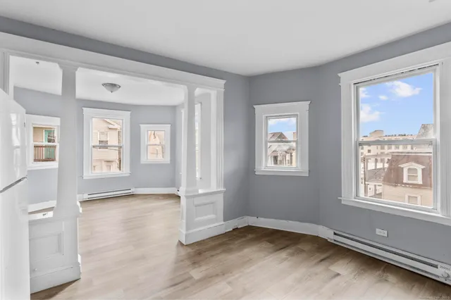 a view of an empty room with wooden floor and a window