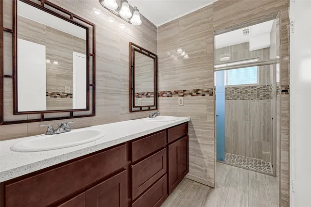 a bathroom with a double vanity sink a mirror and a shower