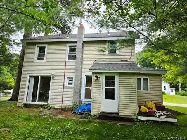 a view of a white house with a yard and a large tree