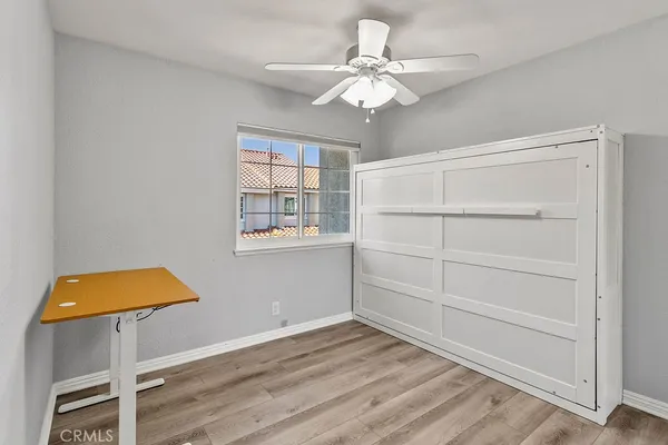a view of patio with chairs and table under an umbrella with barbeque grill and wooden fence