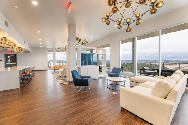 a living room with furniture large window and wooden floor
