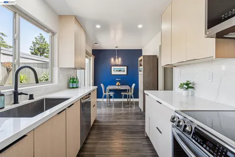 a kitchen with stainless steel appliances granite countertop a sink a stove and a wooden floors