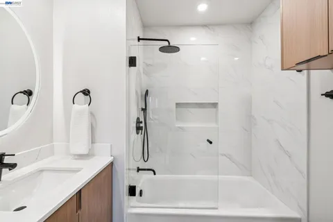a bathroom with a tub sink vanity and mirror