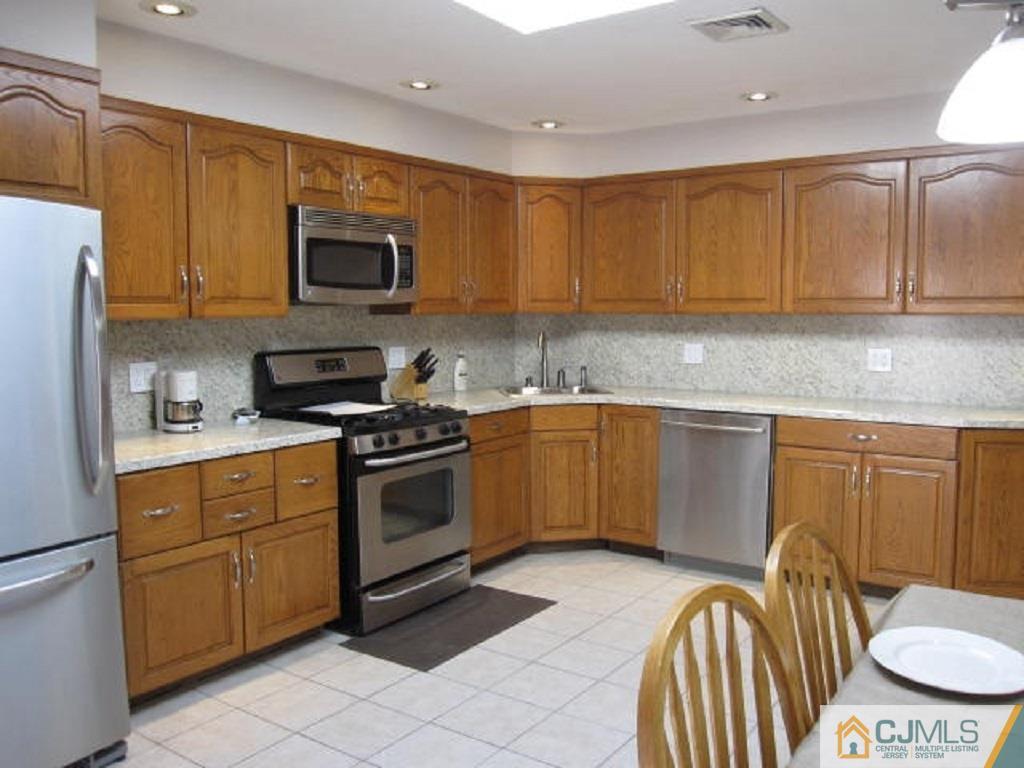 20 Mockingbird Road Edison, NJ 08820 - Photo 8 of 18 a kitchen with stainless steel appliances a stove a sink a microwave a refrigerator and cabinets