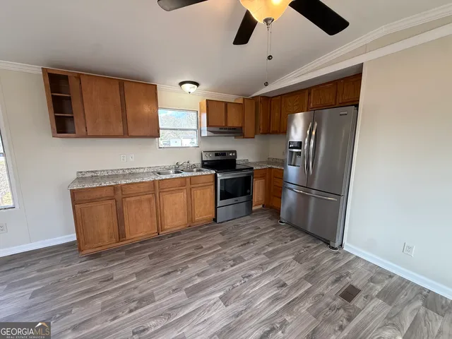 a kitchen with stainless steel appliances granite countertop a refrigerator a sink a stove and a microwave oven with cabinets