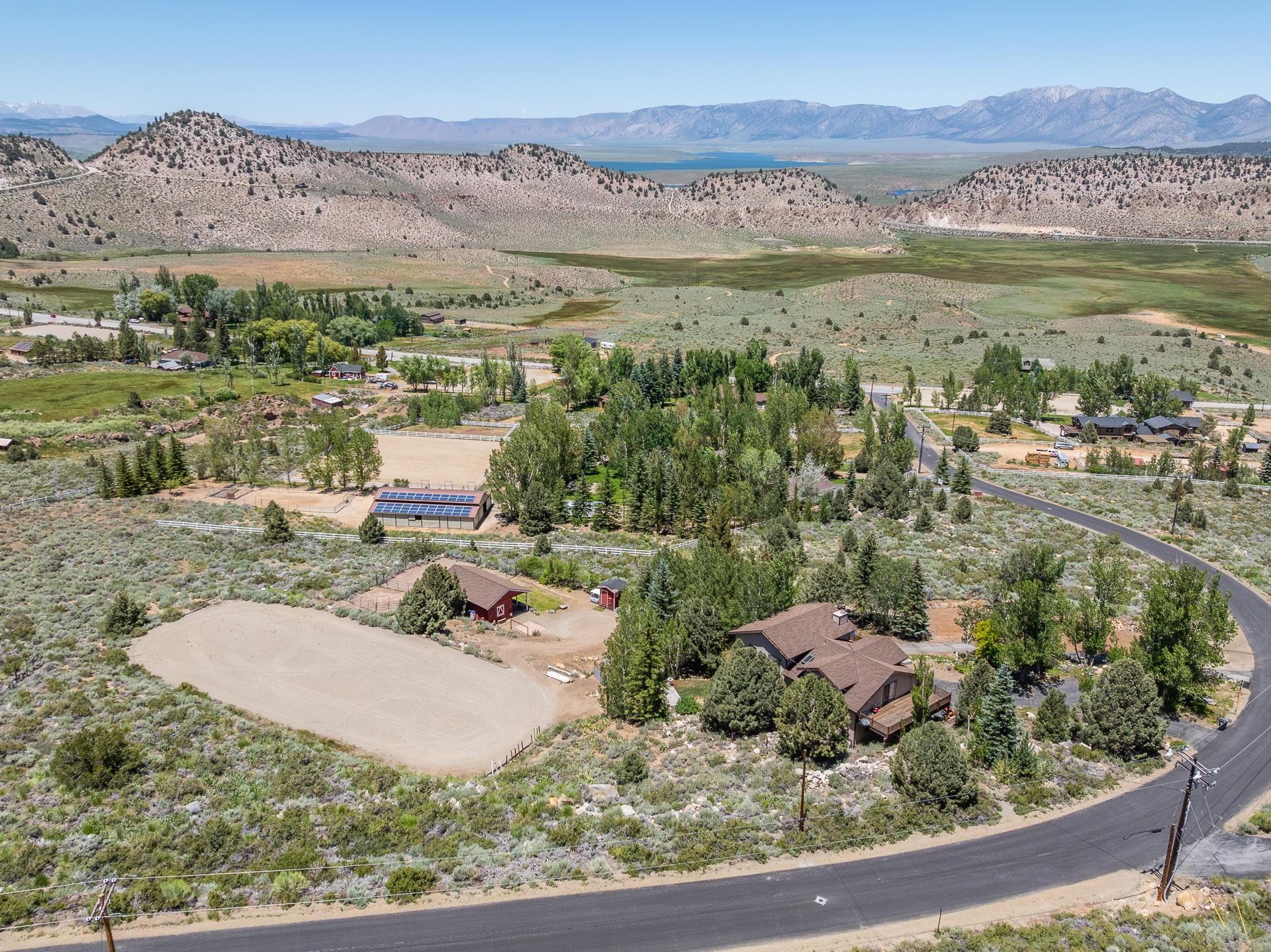 537 Aspen Spring Ranch Road Mammoth Lakes, CA 93546 - Photo 40 of 40 Expansive property featuring a brown multi-level residence with a shingled roof, a large unpaved riding arena, and a red barn structure