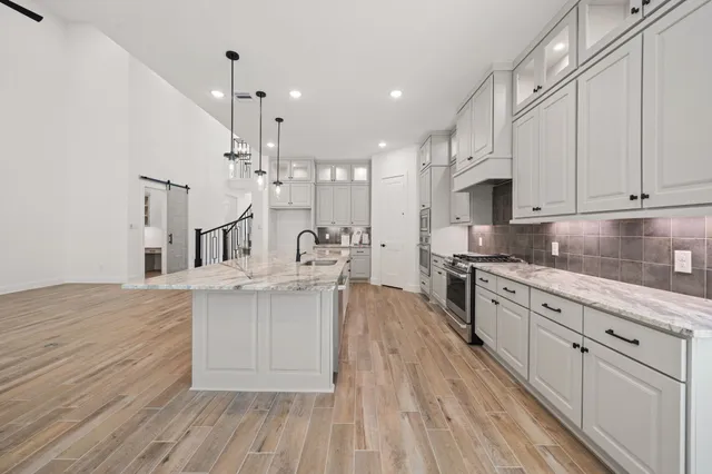 a large kitchen with cabinets wooden floor and stainless steel appliances