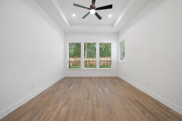 an empty room with wooden floor and windows