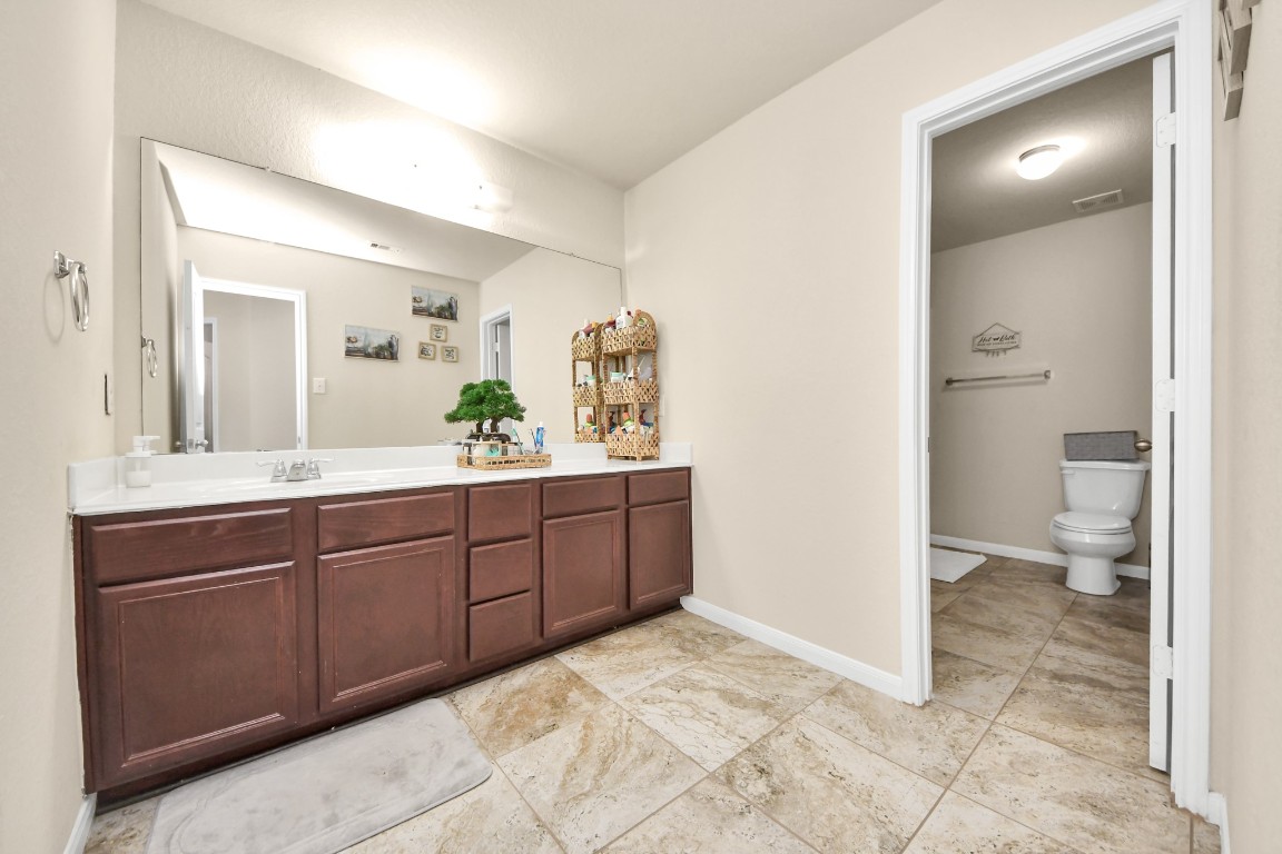 10207 Moonset Lane Houston, TX 77016 - Photo 22 of 34 a spacious bathroom with a granite countertop sink and a toilet