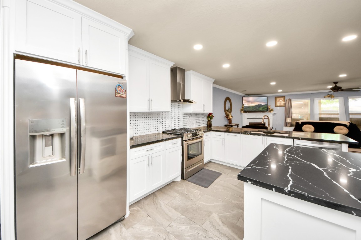 10207 Moonset Lane Houston, TX 77016 - Photo 5 of 34 a large kitchen with a refrigerator a sink and a stove top oven with wooden floor