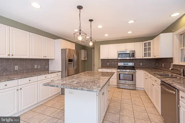 a kitchen with stainless steel appliances kitchen island granite countertop a sink stove and refrigerator