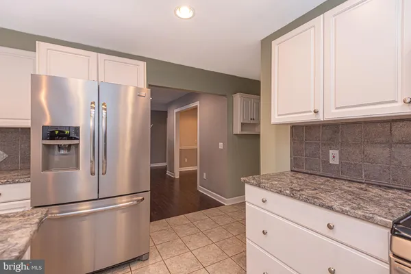 a kitchen with granite countertop a refrigerator and a stove top oven