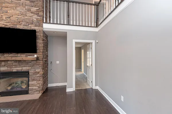 a view of an empty room with wooden floor fireplace and a window