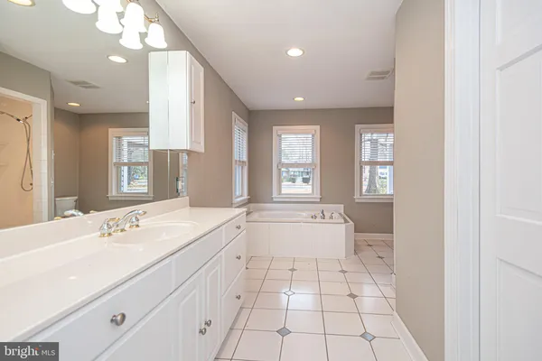 a spacious bathroom with a bathtub sink mirror and toilet