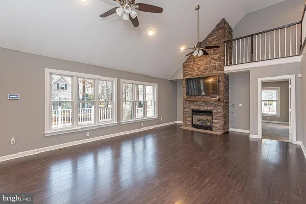 a view of an empty room with wooden floor fireplace and a window