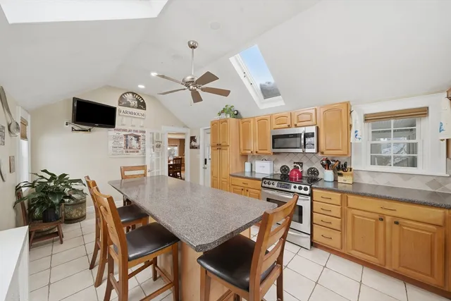 a kitchen with stainless steel appliances kitchen island granite countertop a stove a sink dishwasher a dining table and chairs with wooden floor