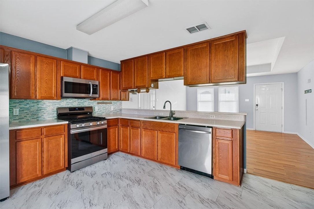 850 Purdue Road Corpus Christi, TX 78418 - Photo 16 of 39 a kitchen with stainless steel appliances granite countertop wooden cabinets a stove a sink and a microwave