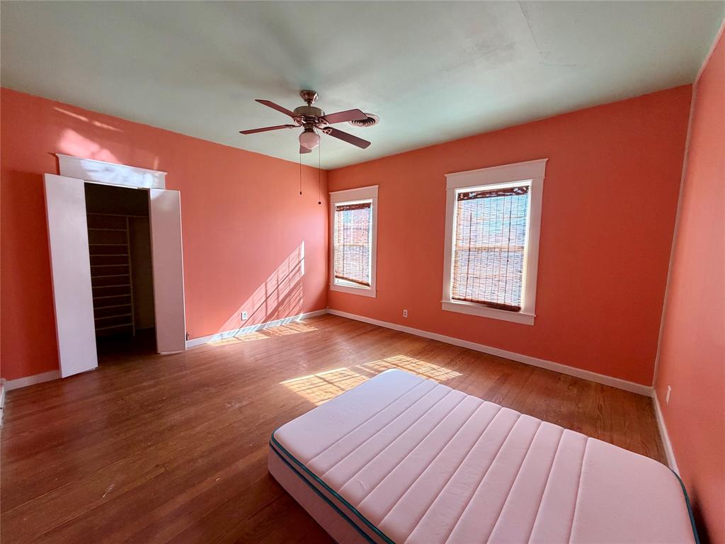 600 Mercer Street Quanah, TX 79252 - Photo 21 of 28 a view of a livingroom with wooden floor a ceiling fan and windows