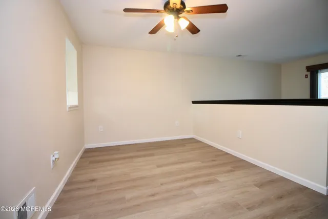 an empty room with wooden floor fan and windows
