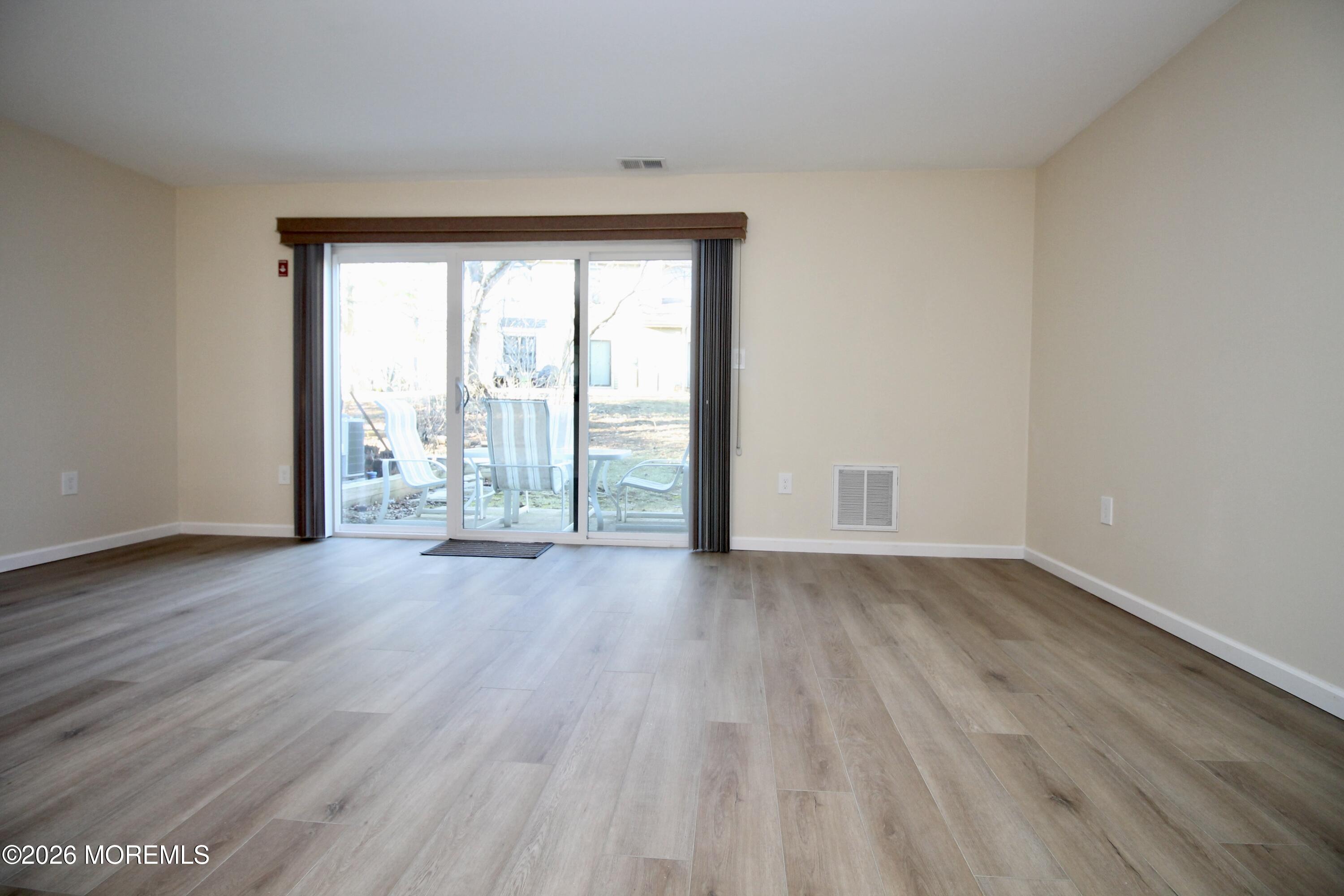 5-2 Claridge Court, Unit 2 Freehold, NJ 07728 - Photo 19 of 35 a view of an empty room with wooden floor and a window