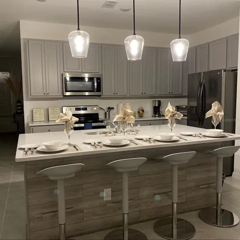 a kitchen with kitchen island granite countertop a sink a counter top space appliances and cabinets