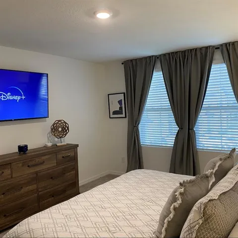 a bedroom with a bed and a flat tv screen on dresser
