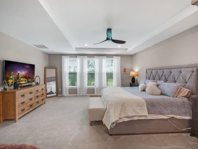 a spacious bedroom with a bed and a flat screen television