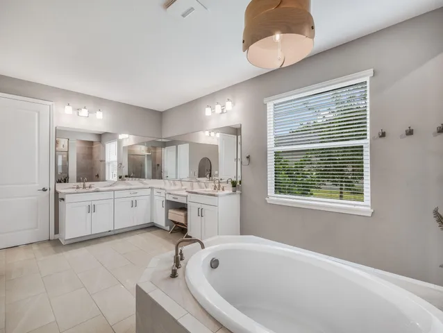 a large white bathroom with a large tub sink shower and mirror