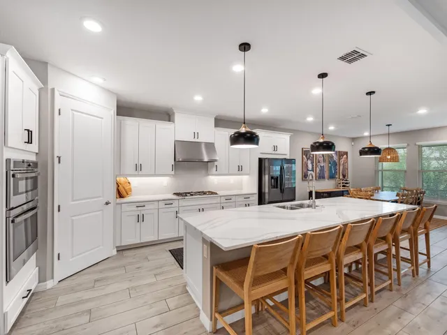 a kitchen with stainless steel appliances kitchen island granite countertop a table chairs and a refrigerator
