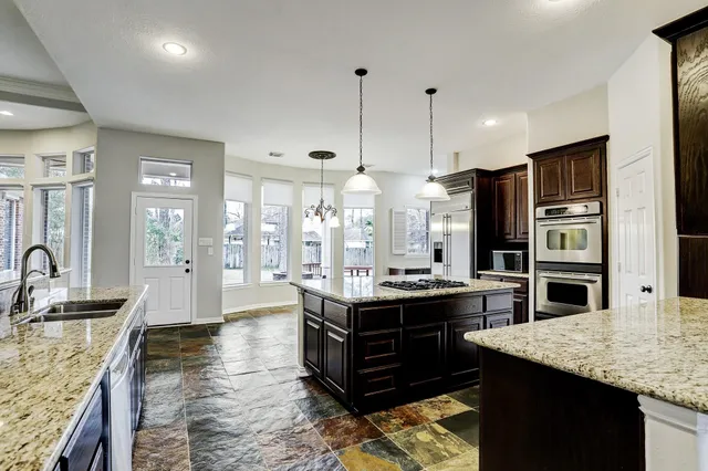 a kitchen with stainless steel appliances granite countertop a stove a refrigerator and a sink