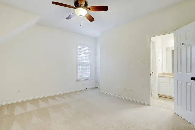 an empty room with chandelier fan and windows