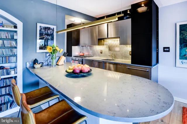 a dining room with stainless steel appliances kitchen island granite countertop a dining table chairs and couches