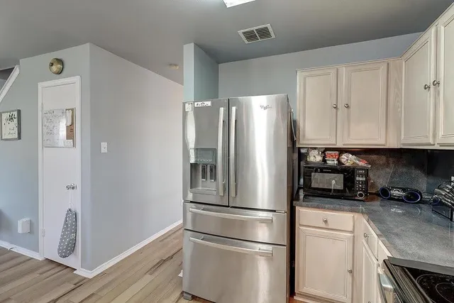 a kitchen with stainless steel appliances a refrigerator a sink and white cabinets