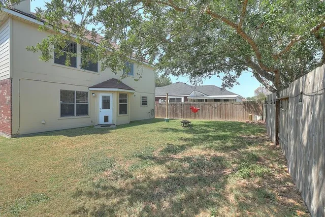 a view of a house with a yard and large tree