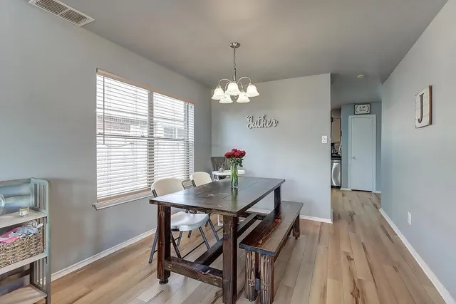 a dining room with chandelier and wooden floor