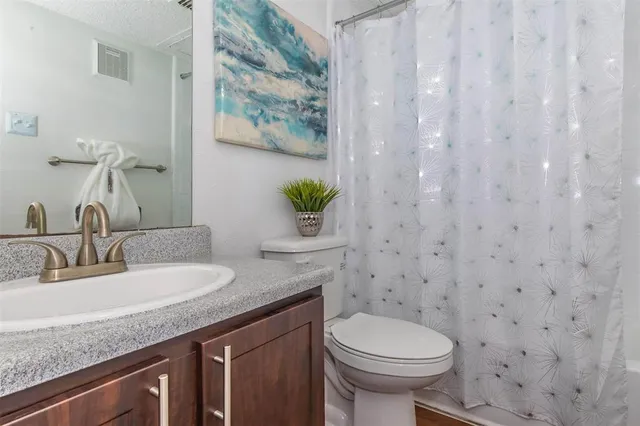 a bathroom with a granite countertop sink and a toilet