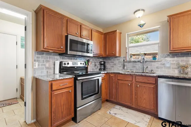 a kitchen with stainless steel appliances granite countertop a stove sink microwave and window