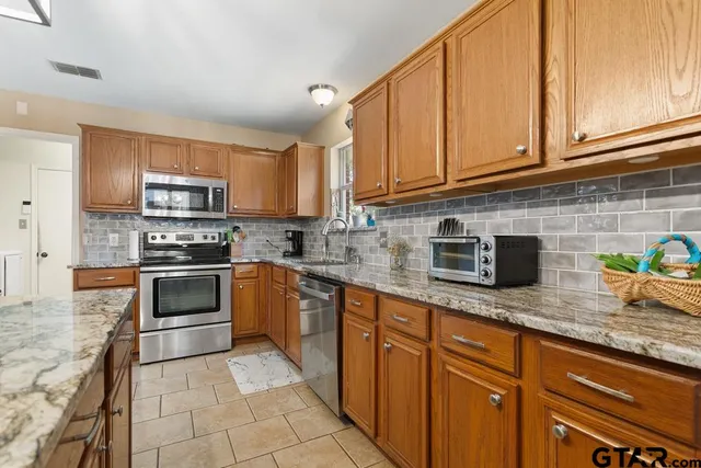 a kitchen with granite countertop a stove top oven microwave and cabinets
