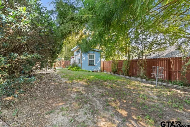 a view of a yard with large trees and wooden fence
