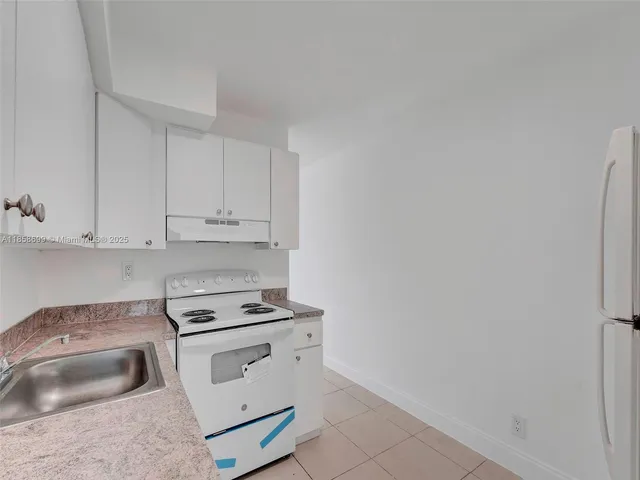 a kitchen with granite countertop white cabinets and white appliances