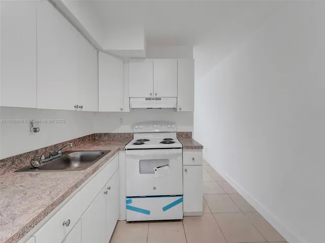 a kitchen with granite countertop white cabinets and white appliances