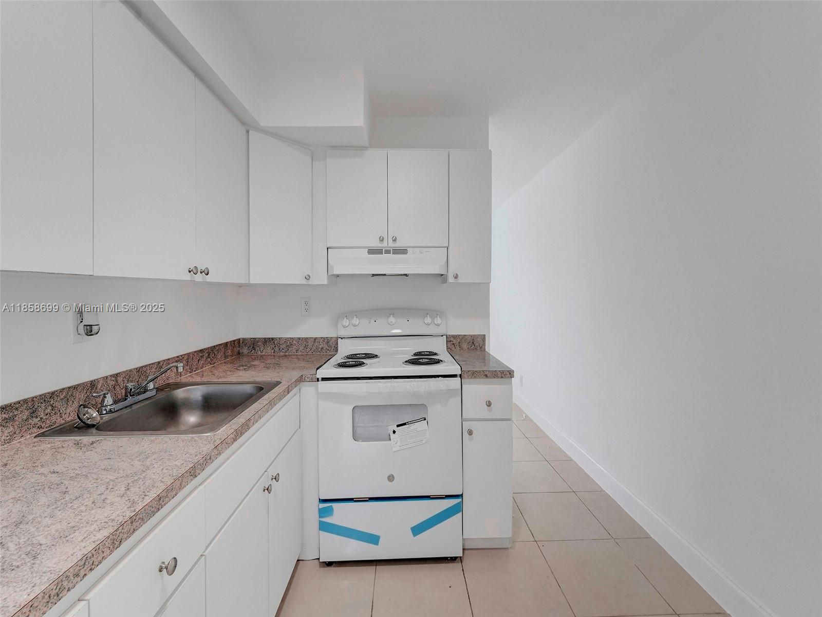 14190 West Dixie Highway, Unit 11 North Miami, FL 33161 - Photo 20 of 21 a kitchen with granite countertop white cabinets and white appliances