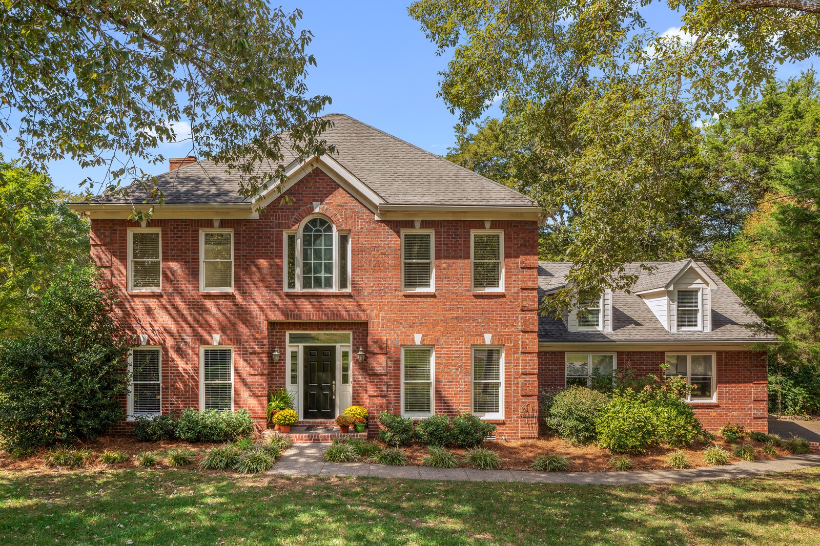 a front view of a house with a yard and potted plants