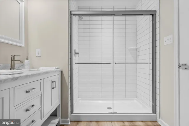 a bathroom with a granite countertop sink a mirror and shower
