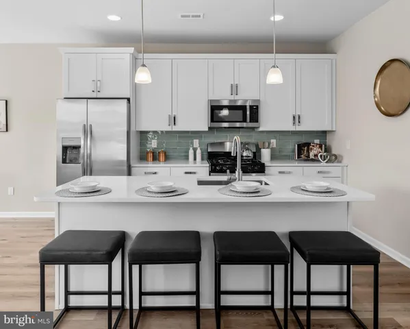 a kitchen with stainless steel appliances a table chairs stove and cabinets